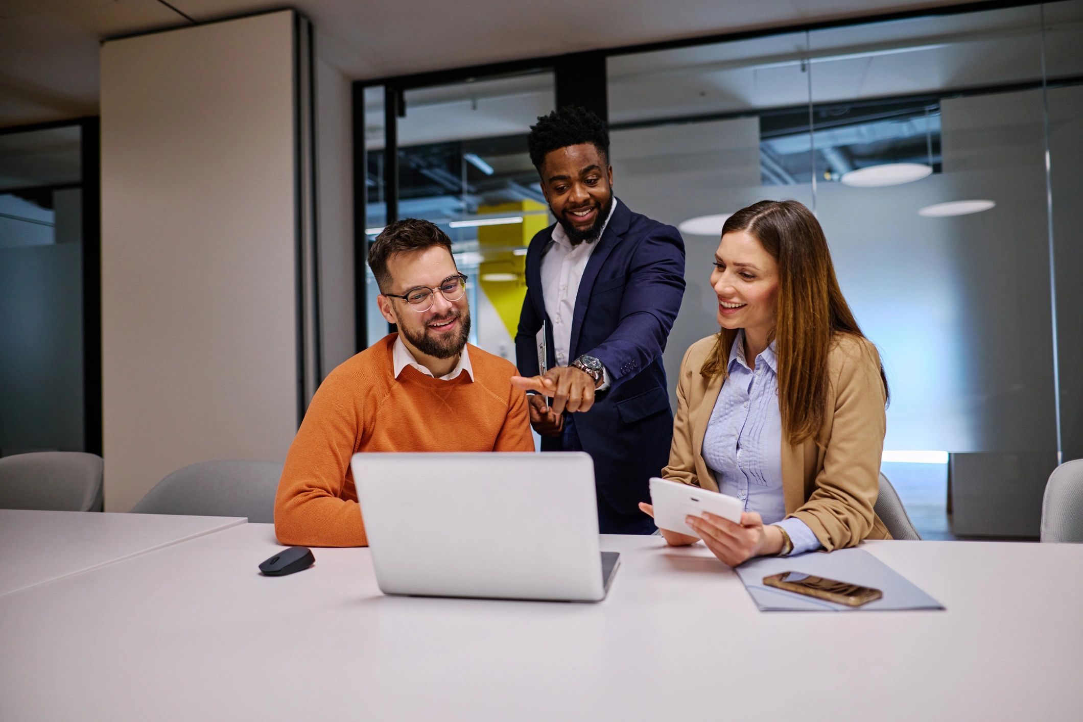 Business team collaborating on marketing strategy around a laptop